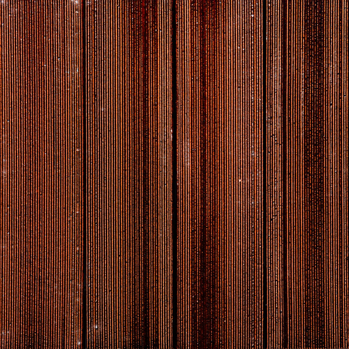 Close-up of vertical rows of Zia Tile's Oxblood + Etched samples, displaying stacked tiles with varying brown tones and textured grooves for a striped effect.