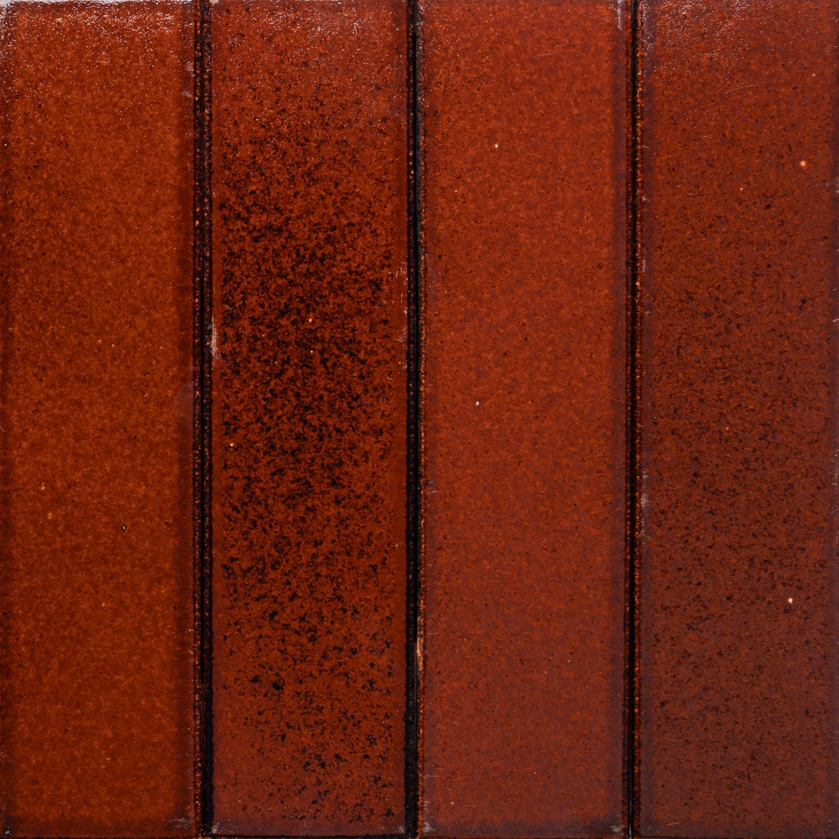 Four vertically aligned Zia Tile Oxblood + Flat, Sample tiles with a slightly speckled glossy reddish-brown finish and thin dark grout lines.