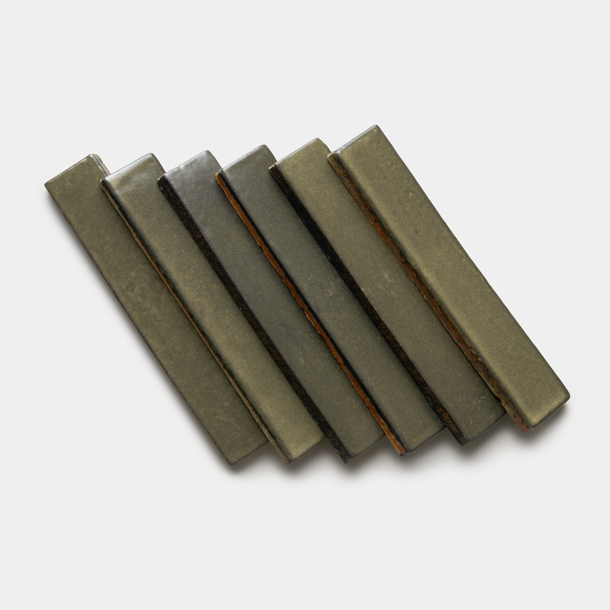 Six rectangular Oyamel Mini Bar tiles by Zia Tile, in olive green ceramic, are arranged diagonally in a staggered, overlapping pattern on a plain white background.