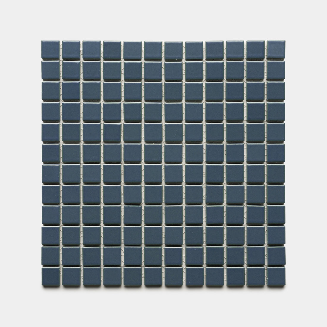 A square grid of Zia Tile's Pacific Blue 1x1 ceramic tiles features small, dark blue squares separated by thin white grout lines, arranged evenly against a plain light background.
