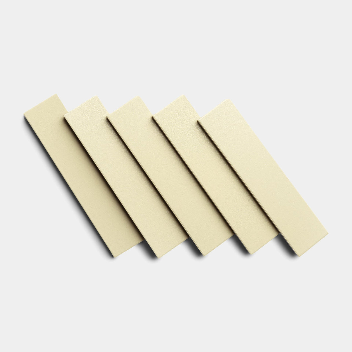 Five Pale Ochre 2x8 sample tiles by Zia Tile are arranged diagonally in a row, slightly overlapping each other, on a plain white background.