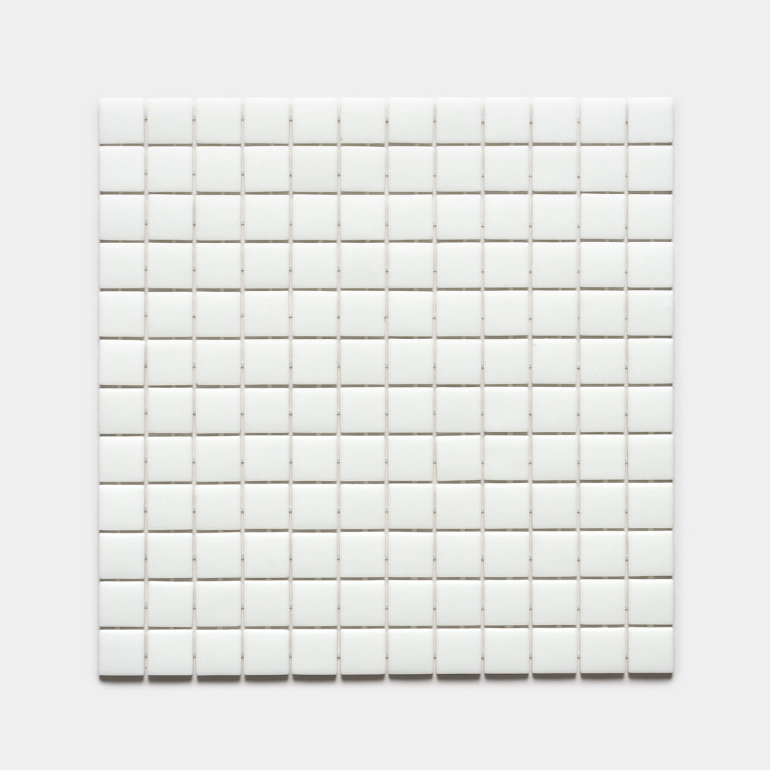 A grid of small, evenly spaced white 1x1 square tiles from Zia Tile’s Paperwhite collection is arranged in a square against a plain white background.