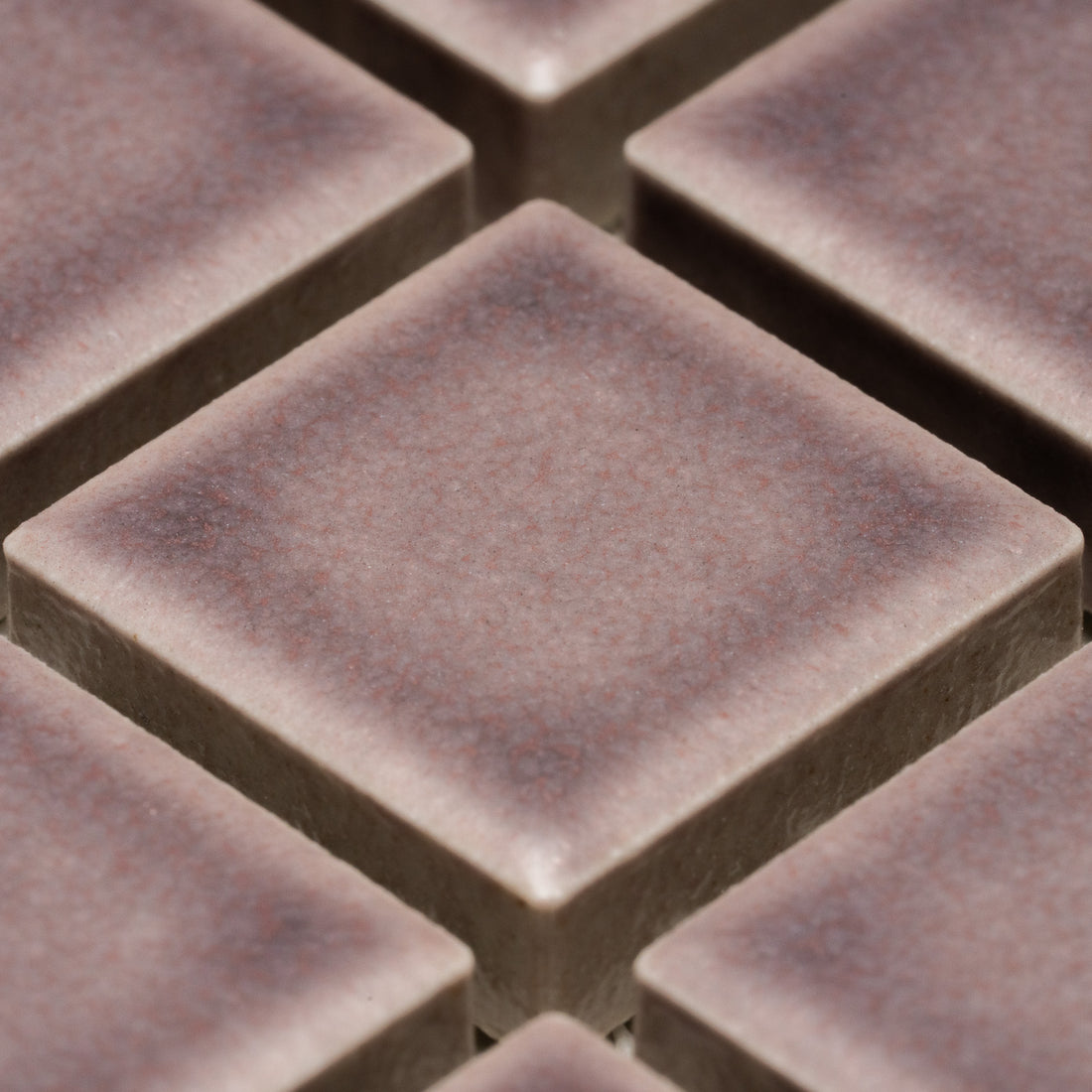 Close-up of Zia Tile's Patchouli 1x1 tiles, featuring square, brownish pieces with a slightly textured matte finish and beveled edges arranged in a diagonal grid pattern.