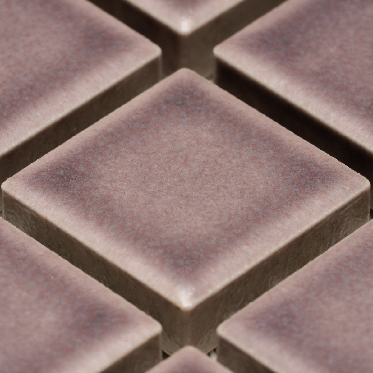Close-up of Zia Tile's Patchouli 1x1 tiles, featuring square, brownish pieces with a slightly textured matte finish and beveled edges arranged in a diagonal grid pattern.