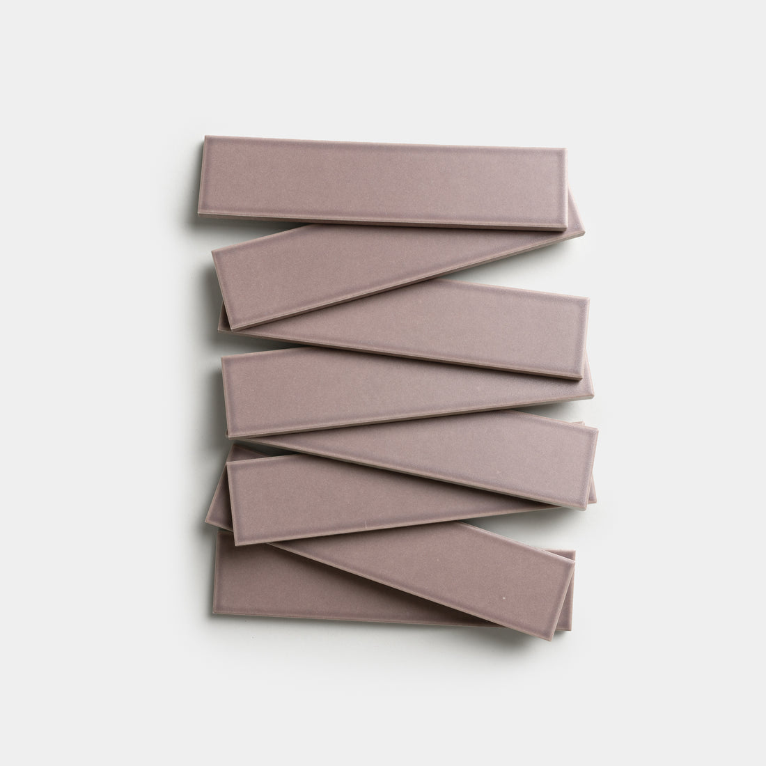 Eight rectangular Patchouli 2x8 tiles by Zia Tile, in a mauve color, are stacked in an alternating, overlapping pattern on a white background.