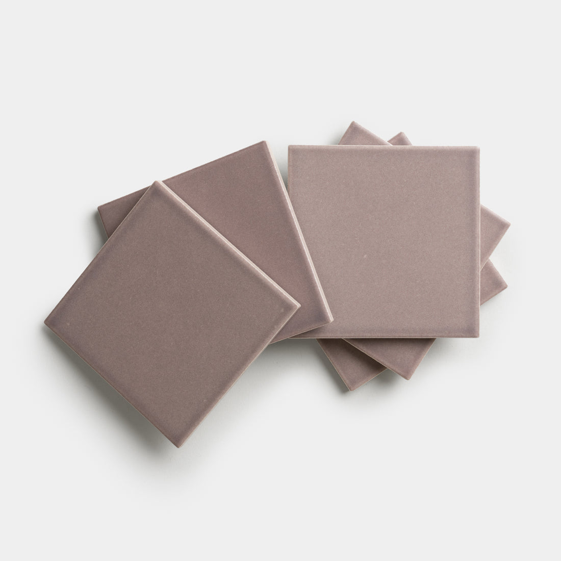 Five Patchouli 4x4 mauve square ceramic tiles by Zia Tile are displayed in a slightly overlapping, fanned-out pattern on a white background.