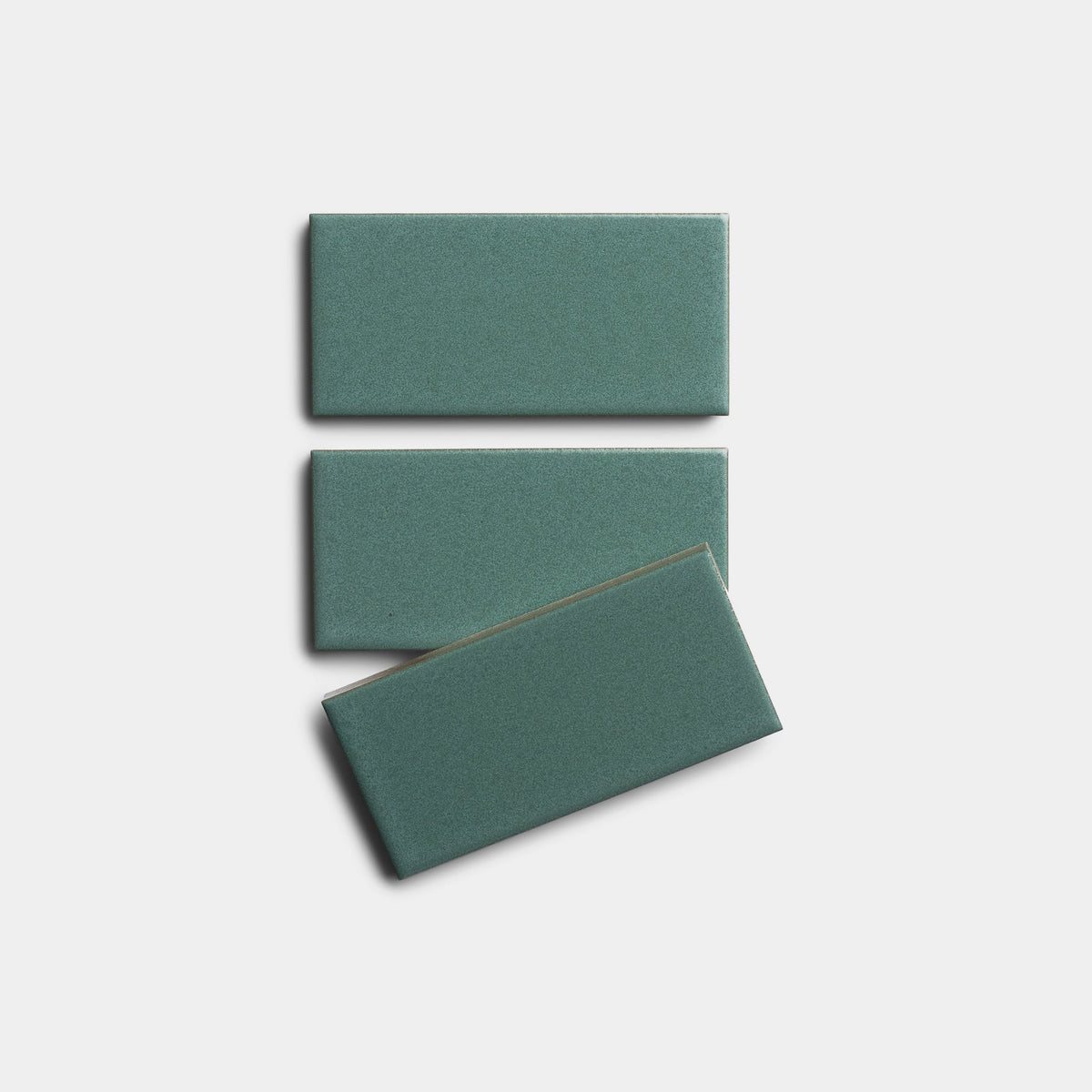 Three rectangular Patina 2x4 green tile samples by Zia Tile are displayed on a white background: two stacked vertically, with a third placed slightly askew below.
