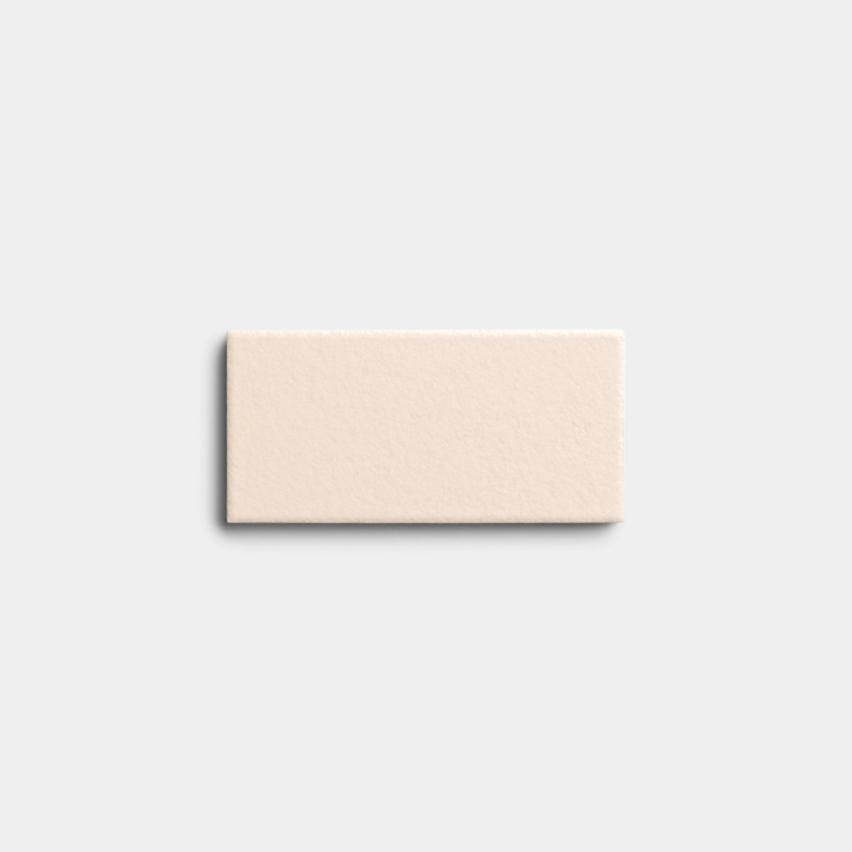 A single Peach Blossom 2x4 sample tile by Zia Tile, rectangular and cream-colored with a slightly textured surface, is centered on a plain, light gray background.