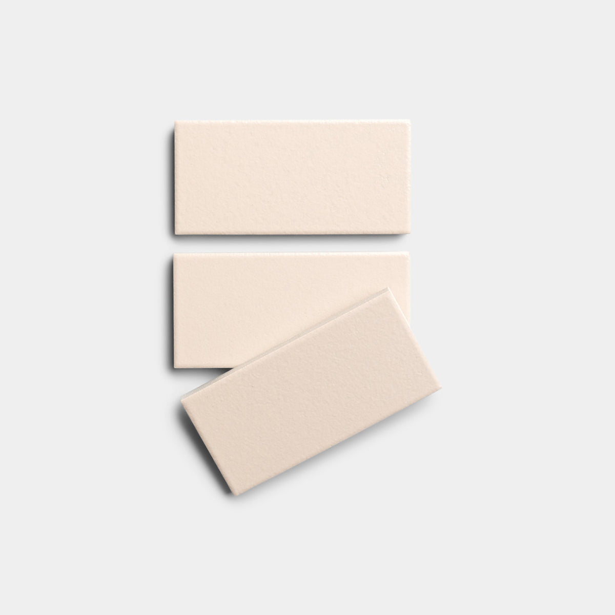 Three rectangular Peach Blossom 2x4 tiles by Zia Tile are arranged vertically on a plain, light gray background. The bottom tile is slightly rotated and overlaps the middle tile.