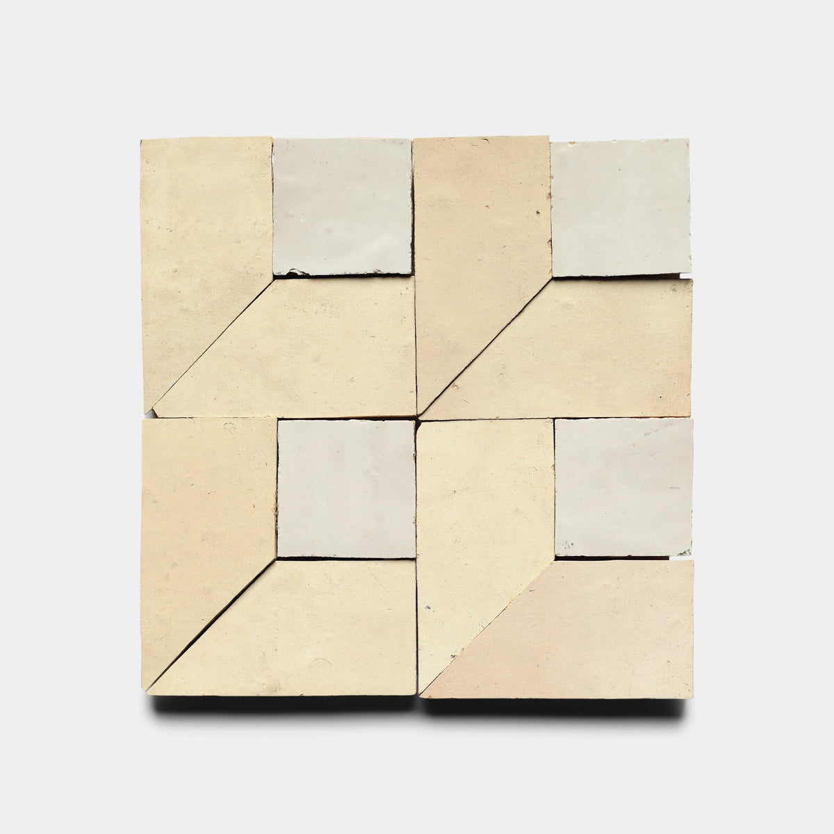 The Perpetual Check 1 sample by Zia Tile features four geometric handmade tiles in beige and off-white, arranged in a square to form an abstract angular pattern with a central diamond shape.