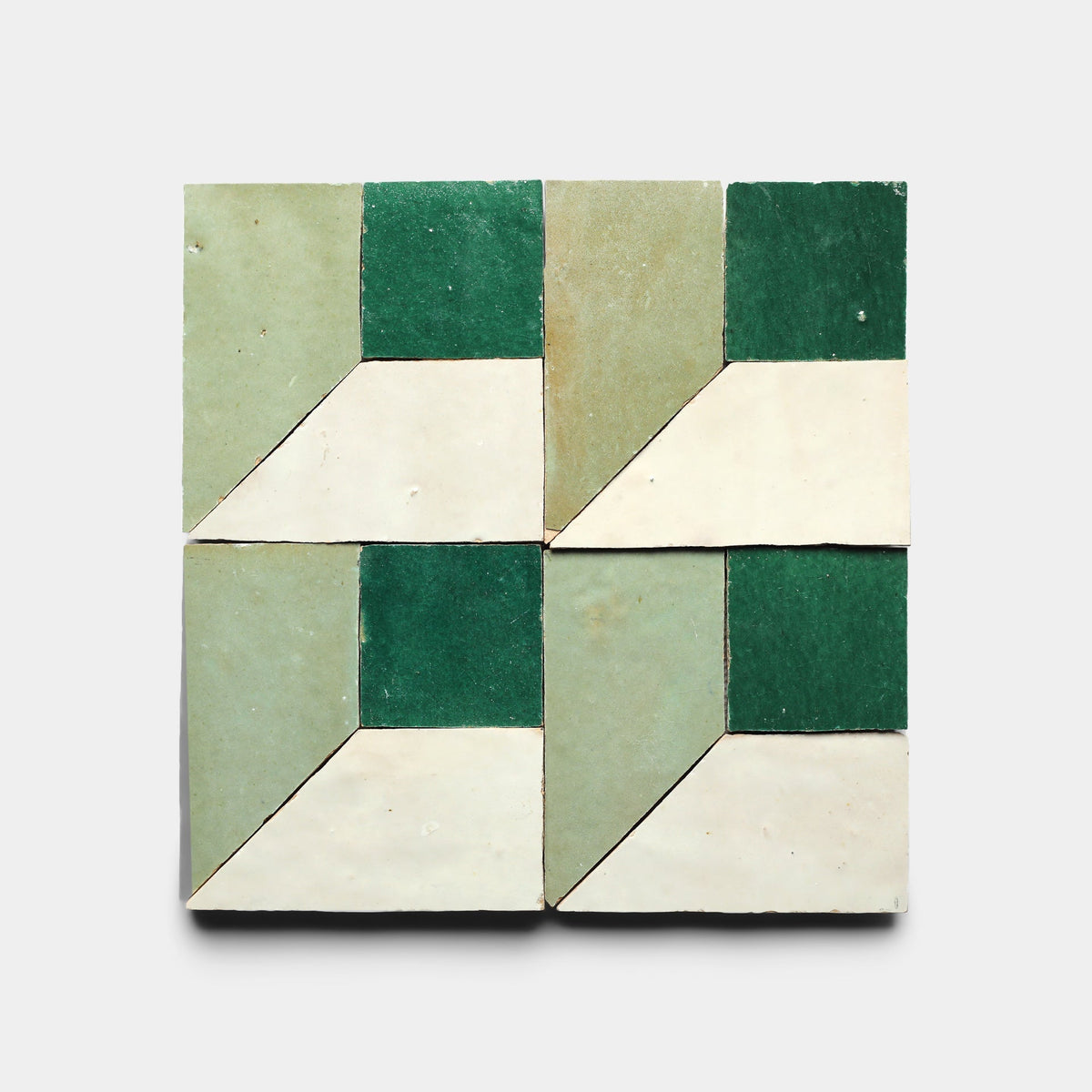 Perpetual Check 2 Sample by Zia Tile features four square ceramic tiles in green, light green, and off-white that form a geometric cube pattern reminiscent of handmade designs, set against a plain light background.