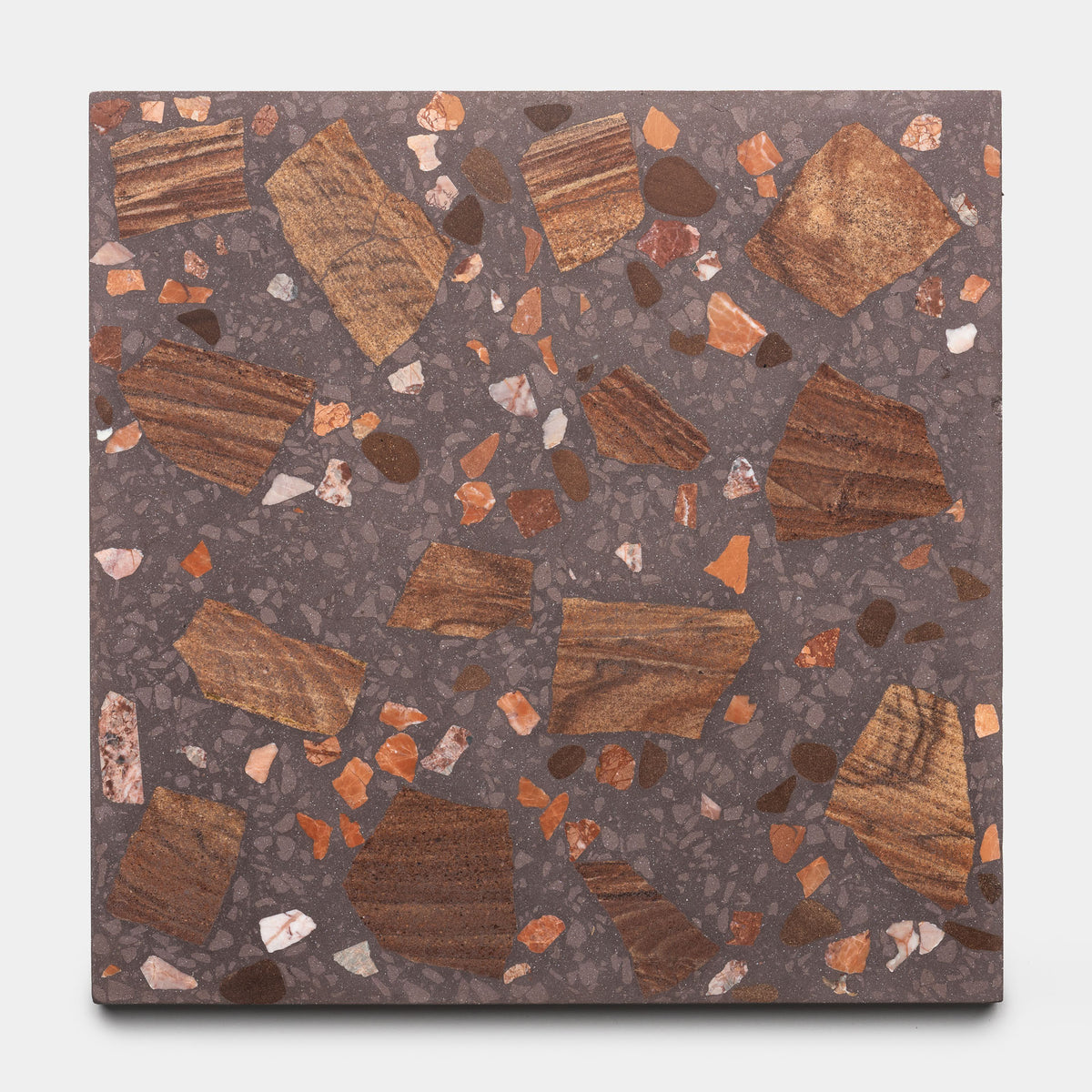 The Zia Tile Petrichor 6x6 sample is a square terrazzo tile with a dark gray base, large irregular brown and orange chips, plus small white and reddish fragments throughout.