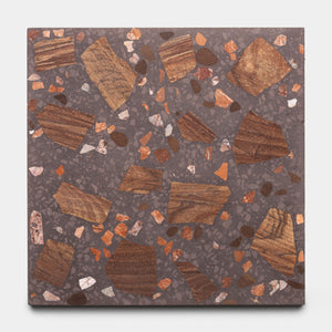 The Zia Tile Petrichor 6x6 sample is a square terrazzo tile with a dark gray base, large irregular brown and orange chips, plus small white and reddish fragments throughout.