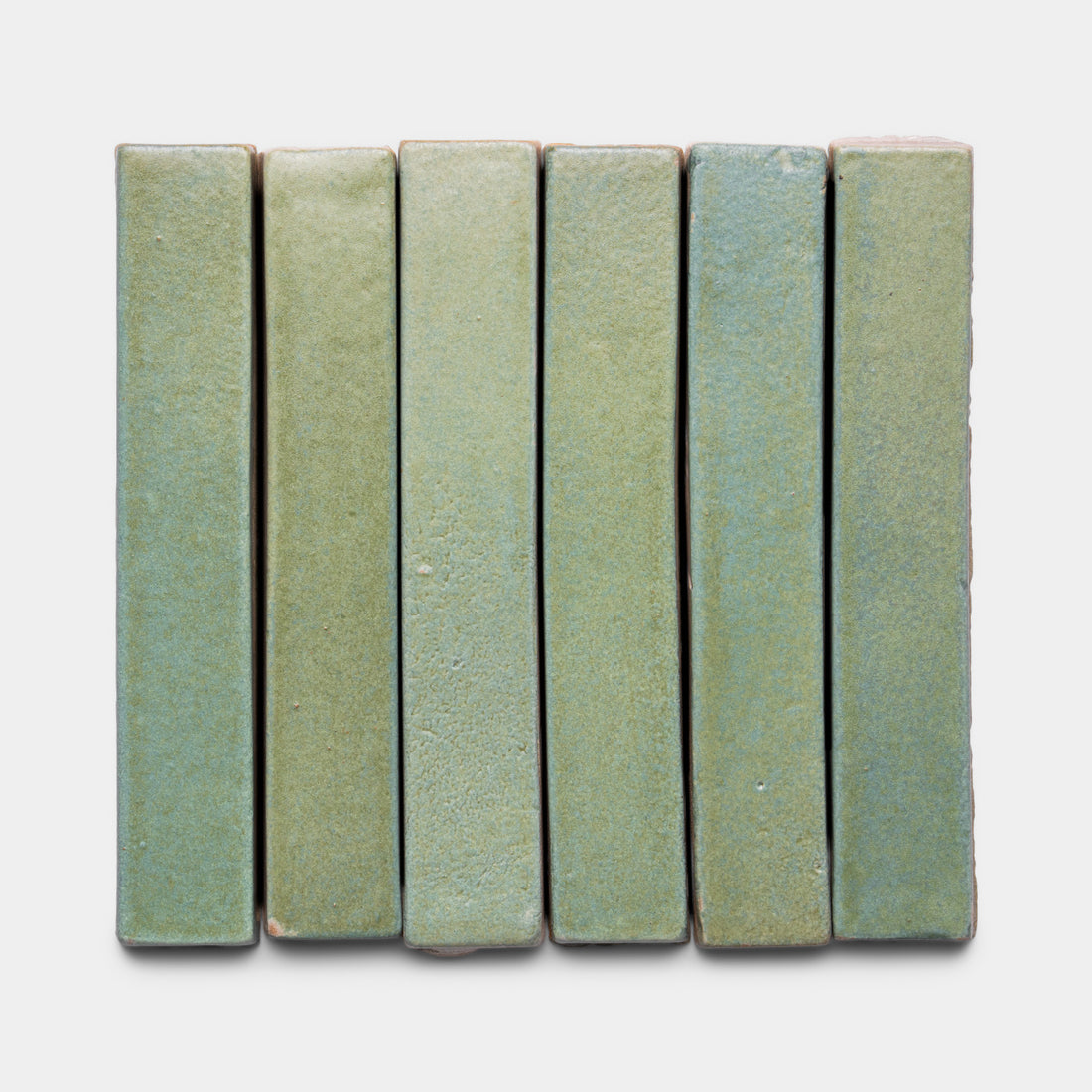 Six rectangular Peyote Mini Bar tiles by Zia Tile, in a green matte ceramic finish with a subtly textured surface, are arranged vertically and closely aligned on a white background.