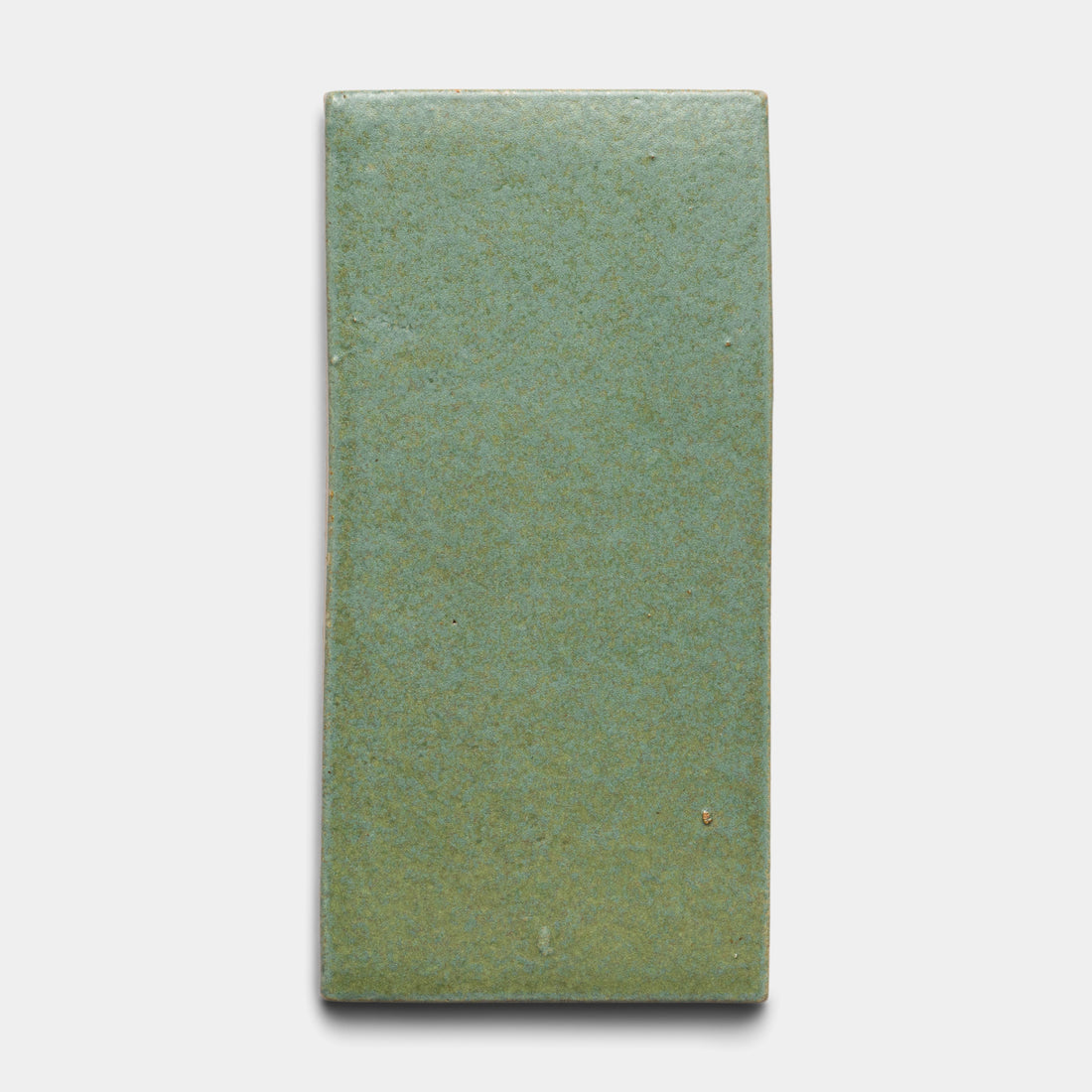 The Peyote 4x8 Rectangle by Zia Tile is a rectangular ceramic tile featuring a smooth, matte greenish-blue finish with subtle specks, shown here on a plain white background.