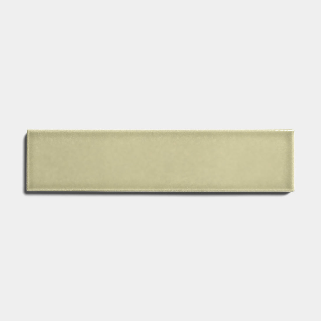The Ponderosa 2x8 by Zia Tile is a rectangular ceramic tile in a light olive green glossy finish, centered on a plain white background to highlight its sleek, architectural grade look.