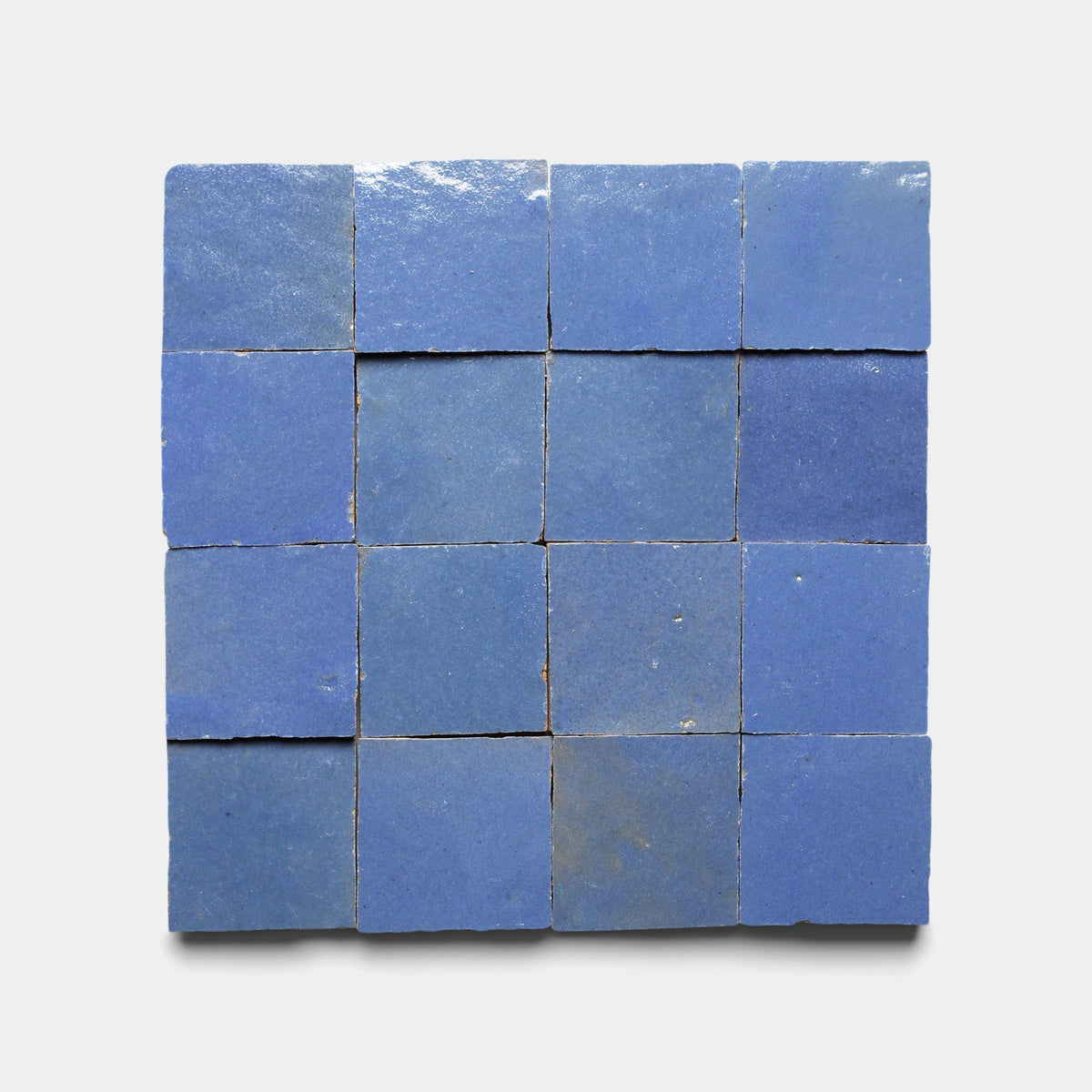 Sixteen Zia Tile Portuguese Blue 2x2 ceramic tiles are arranged in a 4x4 grid on a white background, featuring a slightly glossy finish with subtle shade and texture variations.