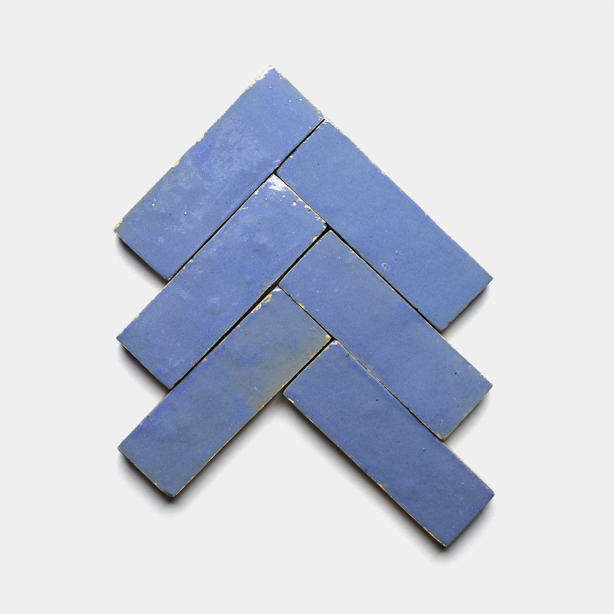 Six rectangular Portuguese Blue 2x6 tiles by Zia Tile are arranged in a herringbone pattern on a white background.