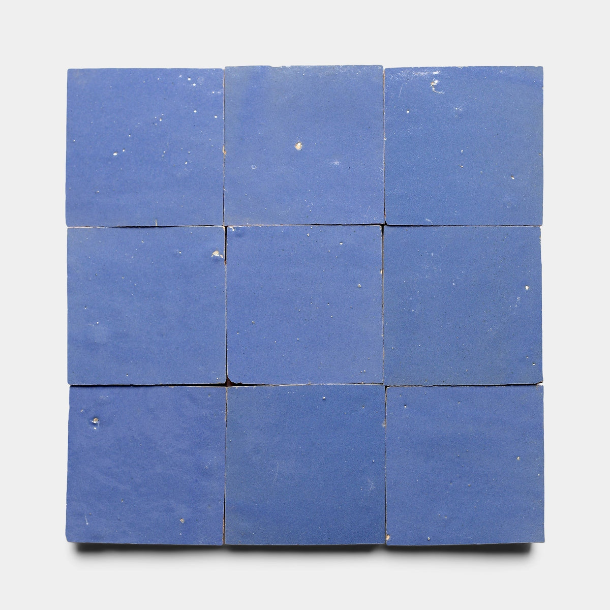 Nine Portuguese Blue 2x6 tile samples from Zia Tile arranged in a 3x3 grid on a white background, showing slight imperfections and small chips on some tiles.