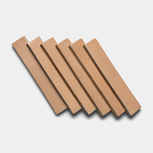 Six Posada Mini Bar rectangular beige ceramic tiles by Zia Tile are arranged diagonally in a row on a white background, casting shadows to the lower right.