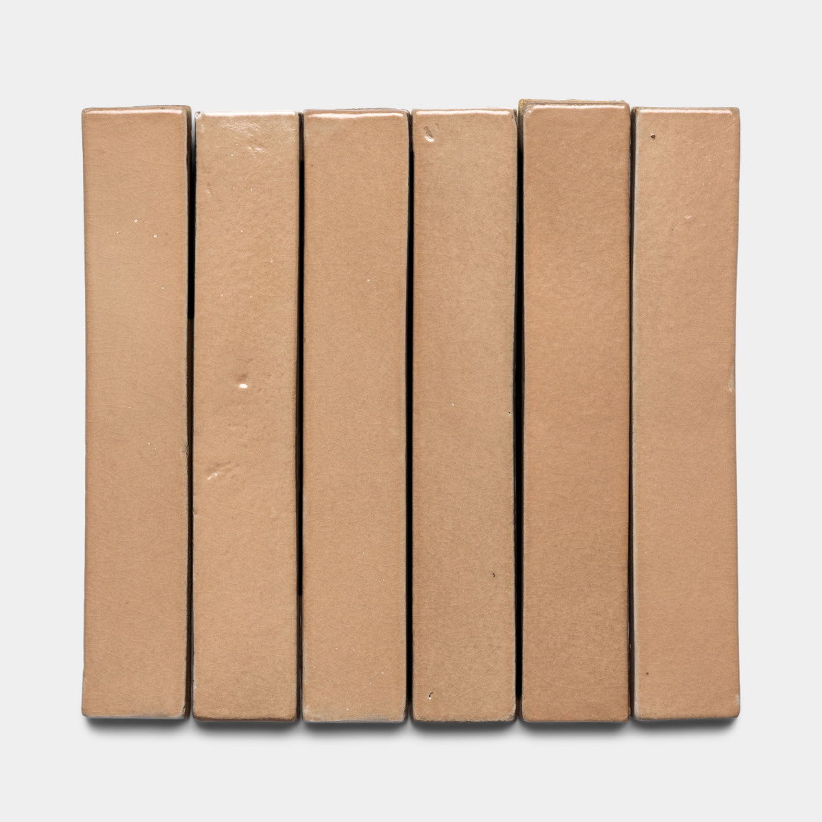 Six rectangular Posada Mini Bar clay tiles by Zia Tile, in light brown, stand vertically side by side on a plain white background.