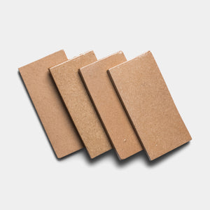 Four Posada 4x8 Rectangle tiles by Zia Tile, in light brown, are arranged diagonally with slight overlap on a white background, casting soft shadows.