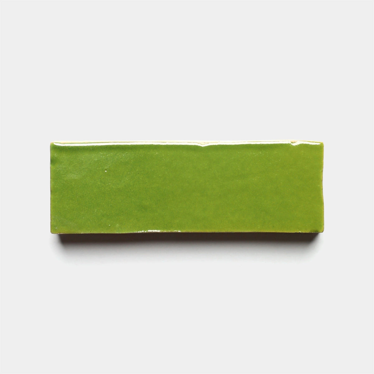A glossy, rectangular Prairie Green 2x6 sample tile by Zia Tile with smooth edges, shown on a plain white background.
