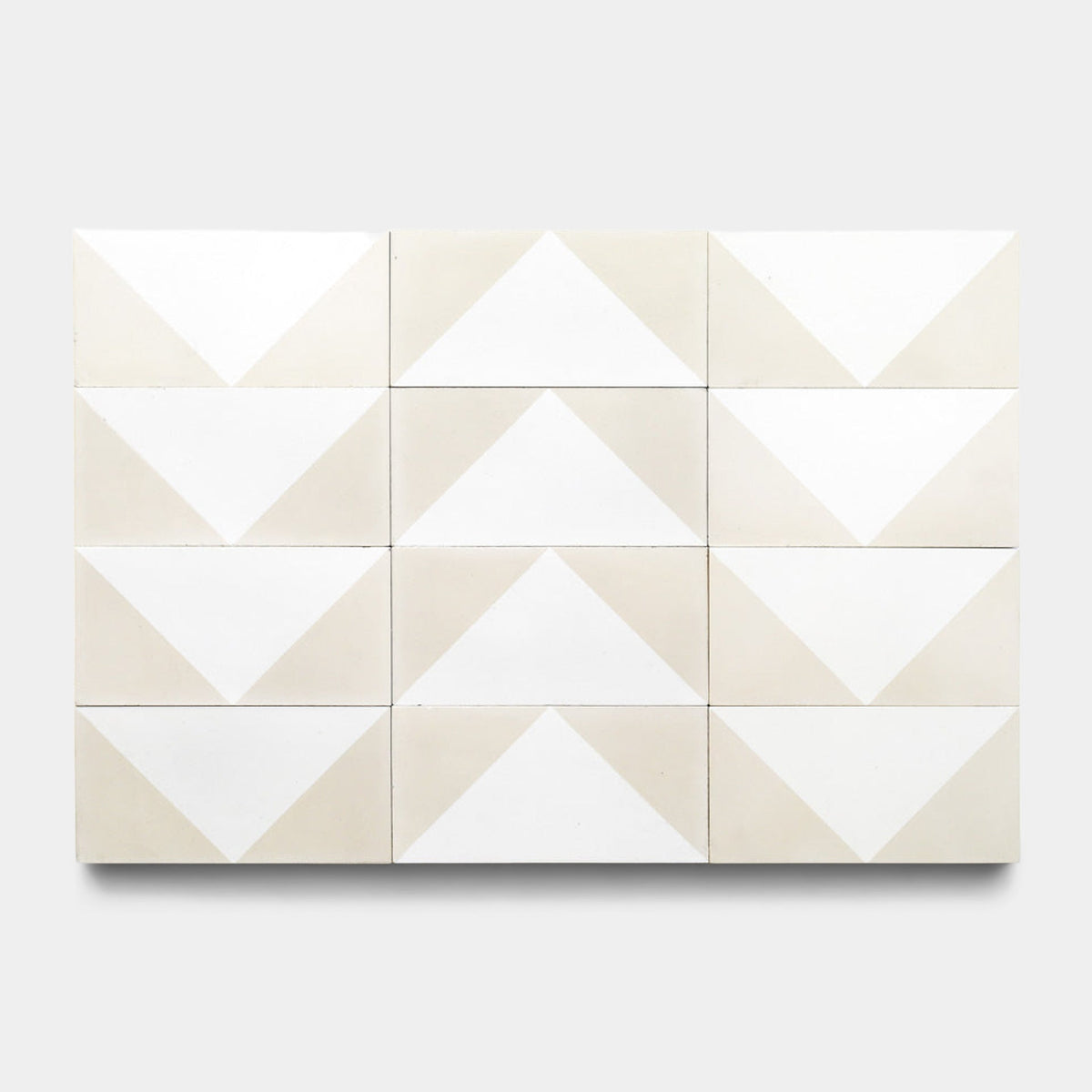 Twelve Press Play Nile 4x8 cement tiles by Zia Tile are arranged in a 3x4 grid, each displaying geometric arrow patterns with white and light beige triangles on a light gray background.