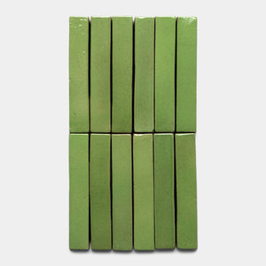 Twelve Primavera Mini Bar tiles by Zia Tile, rectangular and green, are arranged vertically in two columns of six on a plain white background.