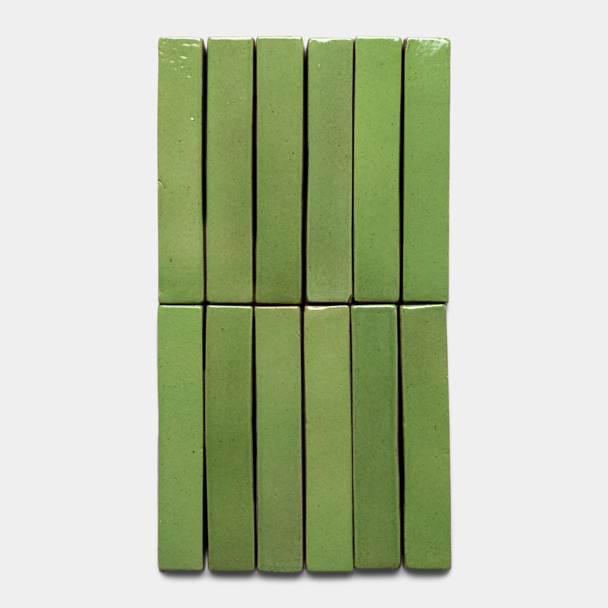 Twelve Primavera Mini Bar tiles by Zia Tile, rectangular and green, are arranged vertically in two columns of six on a plain white background.