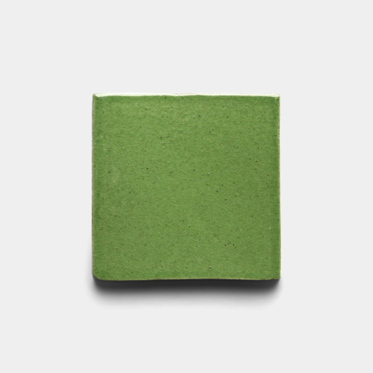 A square, solid green block—Zia Tile's Primavera 4x4 Square Sample—is centered on a plain white background. The smooth, matte surface features subtle texture and clean edges, inspired by Cotto.
