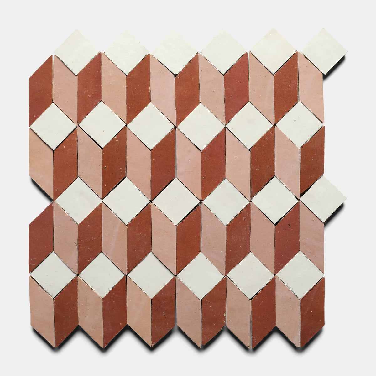 The Prismatic 3 Sample by Zia Tile features a geometric pattern with alternating diamond shapes in white, light pink, and terracotta, creating a 3D cube illusion on a plain white background.