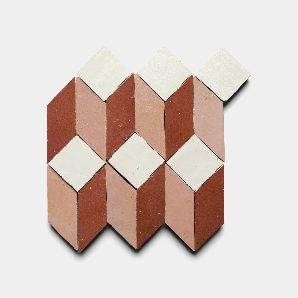 The Prismatic 3 sample from Zia Tile features a geometric pattern of diamonds and parallelograms in red, pink, and white, inspired by handmade designs and arranged in a striking repeat on a white background.