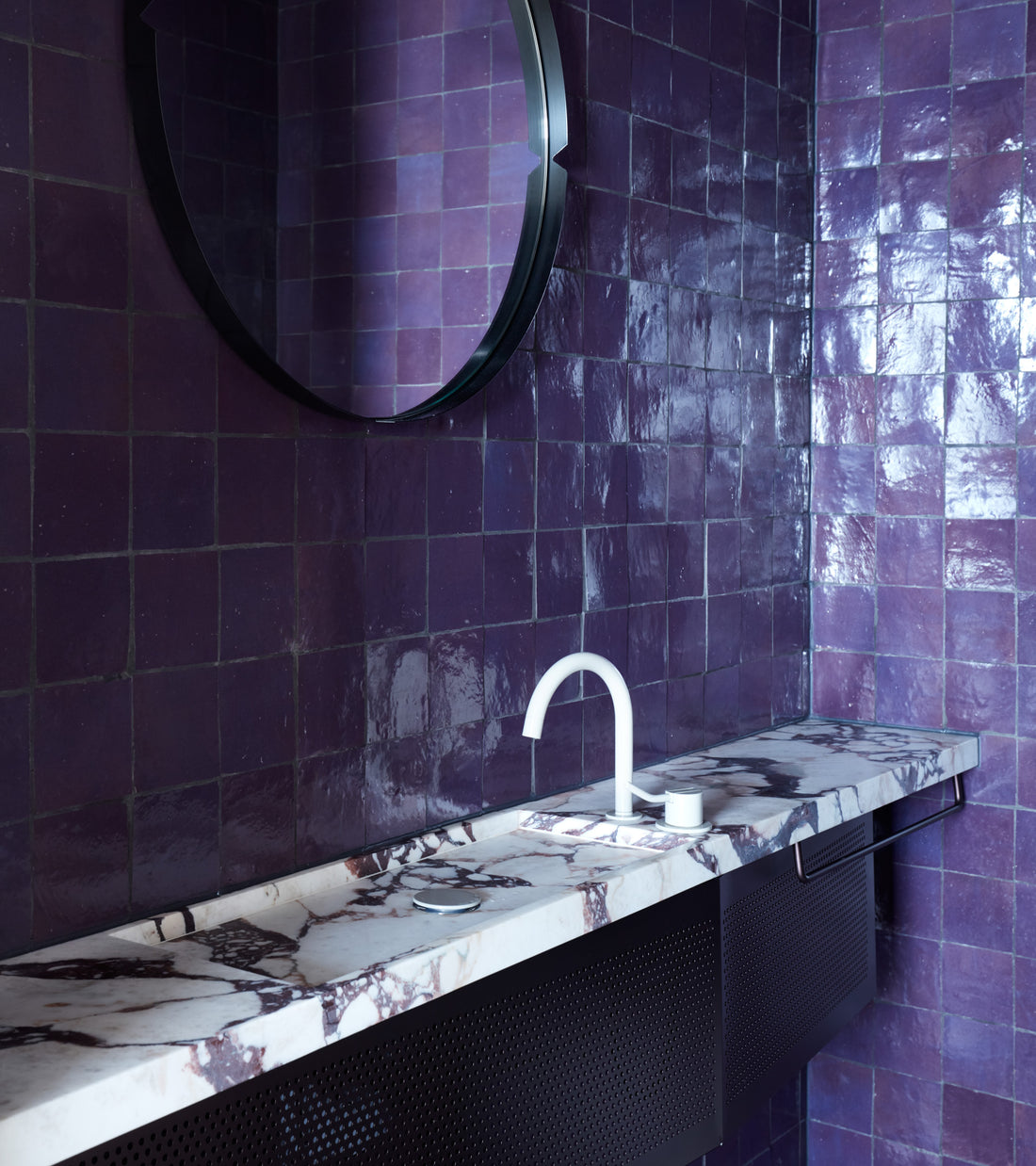 Contemporary bathroom featuring vendor-unknown's Purple Iris 4x4 tiles in a glossy finish, paired with a round mirror, marble countertop, and white faucet with matching soap dispenser.