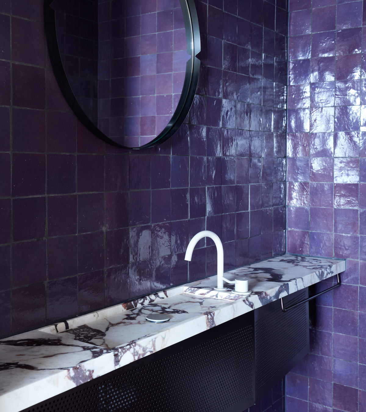 Contemporary bathroom featuring vendor-unknown's Purple Iris 4x4 tiles in a glossy finish, paired with a round mirror, marble countertop, and white faucet with matching soap dispenser.