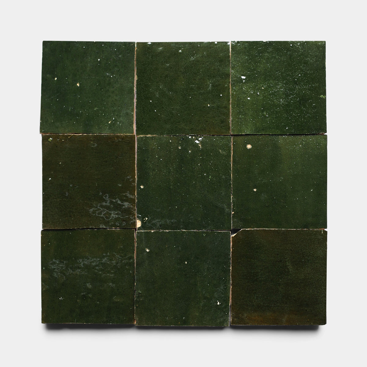 Nine Noble Green 4x4 handmade tiles by Zia Tile, featuring glossy dark green shades and unique imperfections, are arranged in a 3x3 grid on a plain white background.
