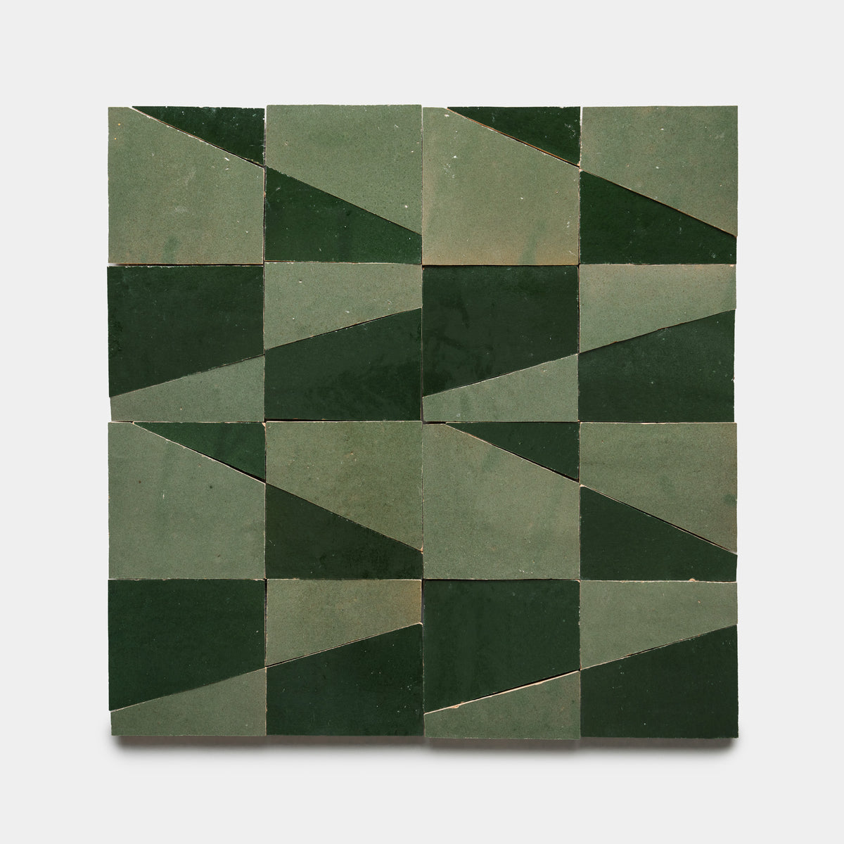 The Atlas 4 by Zia Tile features a square layout of sixteen tiles in four rows and columns, each tile split diagonally into two shades of green to form a striking geometric zigzag pattern.
