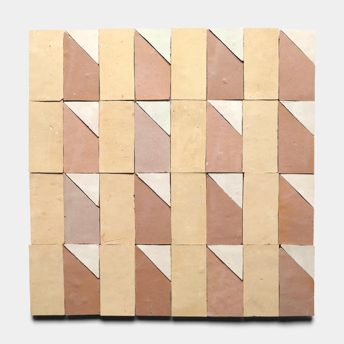 A 5x5 grid of Zia Tile’s Radian Inline 1, Sample ceramic tiles, each handmade and diagonally split into beige and light brown, forms a repeating geometric pattern on a light gray background.