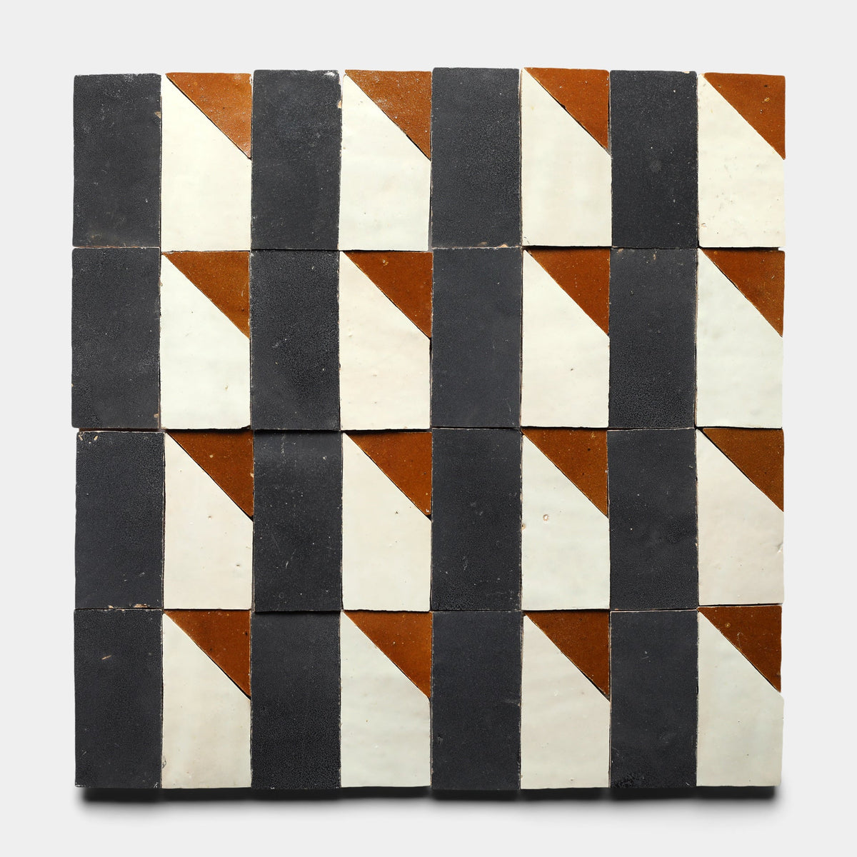 The Radian Inline 2 Sample by Zia Tile features square cement tiles with a geometric pattern of alternating black, white, and brown triangles and rectangles, forming a repeating grid on a light gray background.