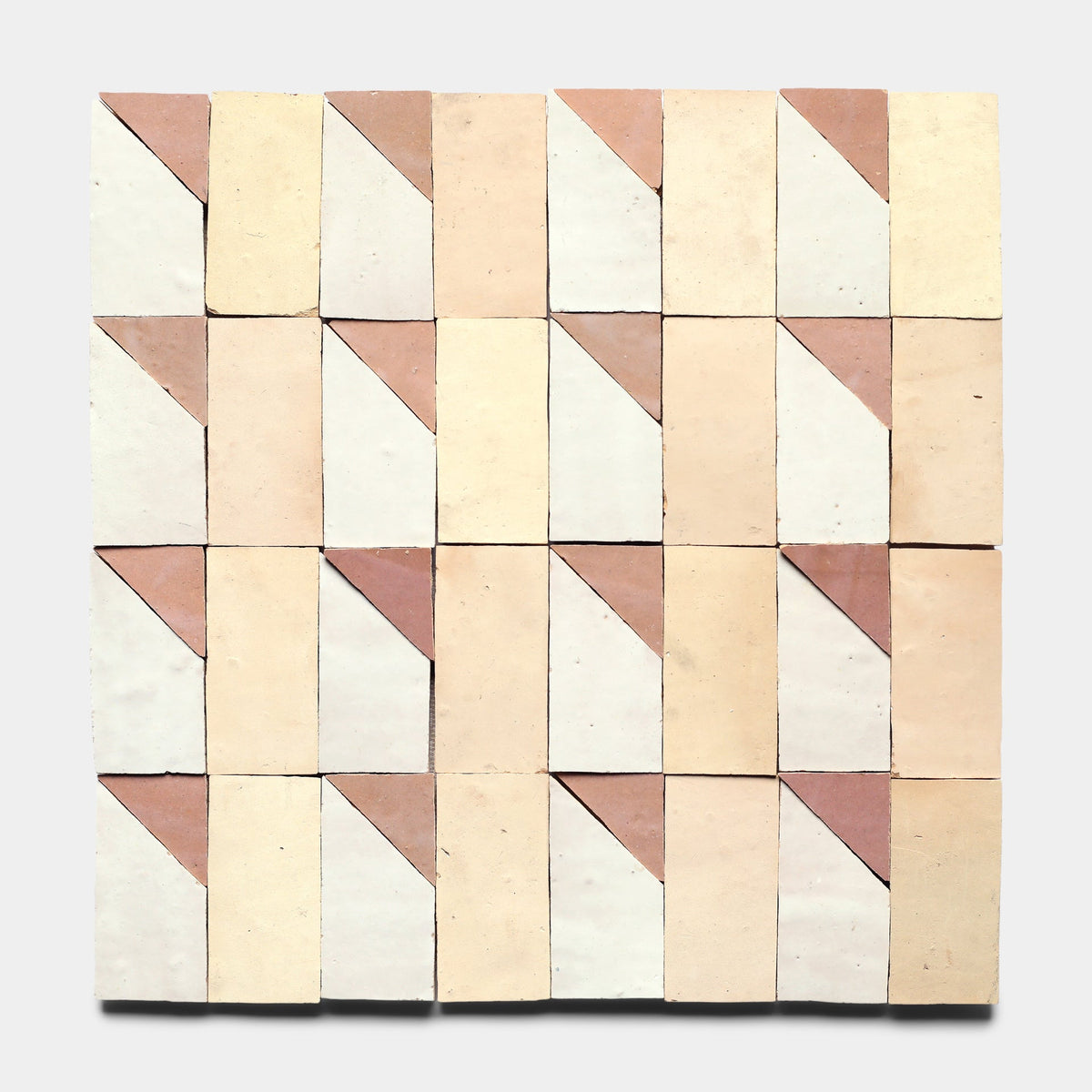 Radian Inline 5 by Zia Tile features rectangular handmade tiles in beige and light pink, arranged in a geometric pattern with diagonal divisions of triangles and rectangles, set against a light gray background.