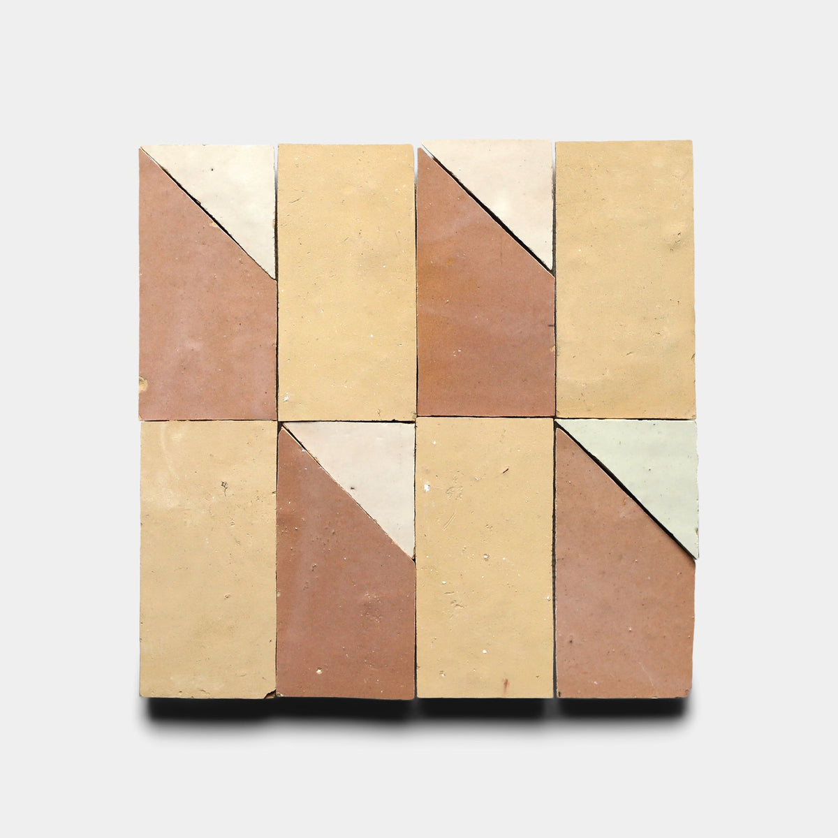 Eight Zia Tile Radian Offset 2 cement tiles, arranged in two rows of four, showcase handmade geometric patterns with diagonal divisions in beige, brown, cream, and pale green on a light gray background.