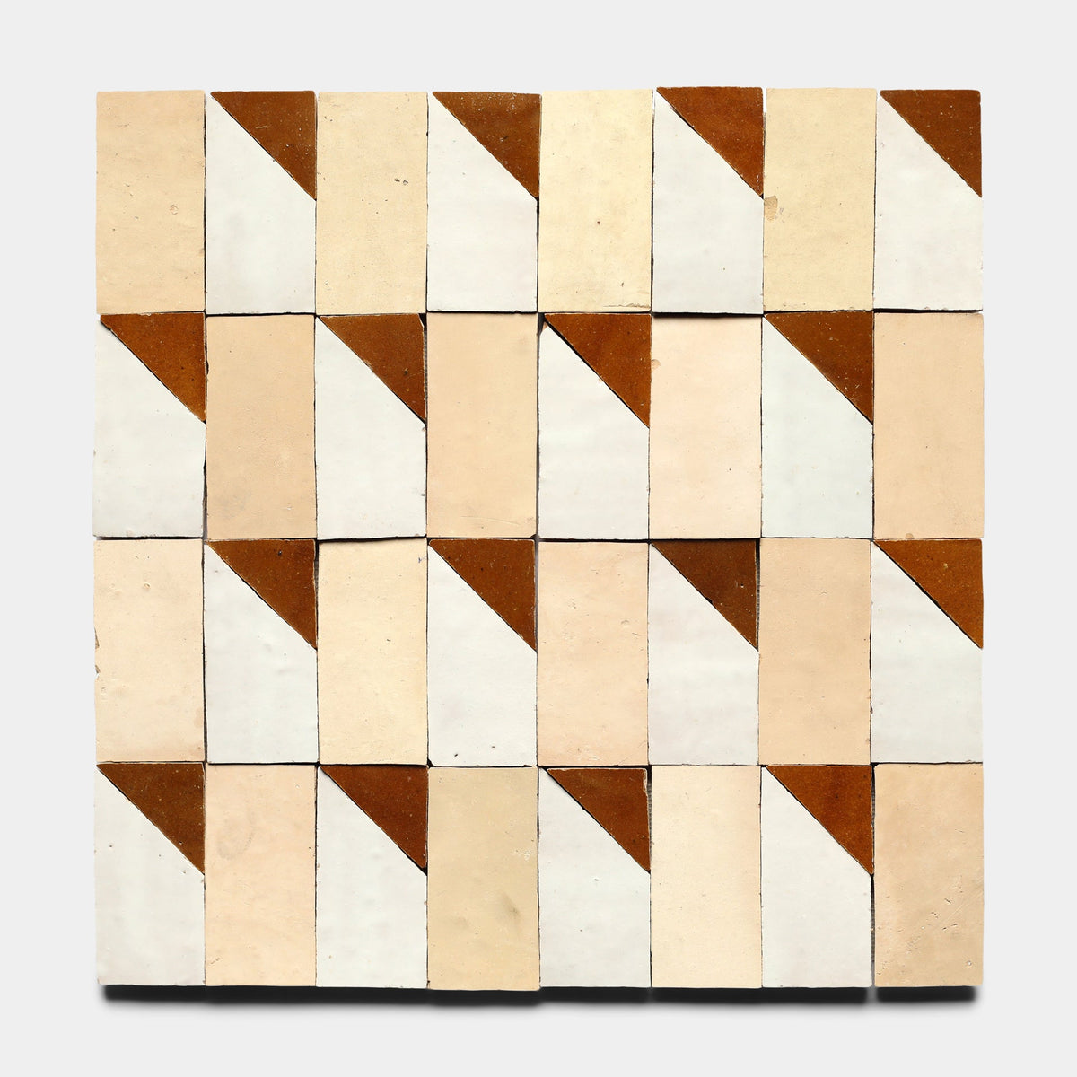 The Radian Offset 6, Sample by Zia Tile features a grid of handmade rectangular tiles in cream, beige, and white with small brown corner triangles, creating a geometric pattern on a light gray background.