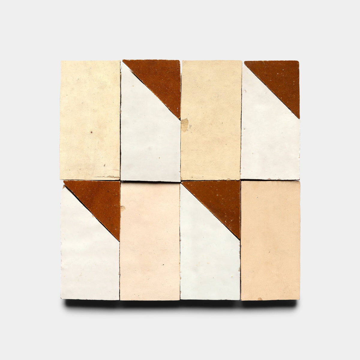 Eight Radian Offset 6 tiles by Zia Tile, handmade and rectangular, are arranged in two rows; each tile features a diagonal brown corner with beige or off-white shades, forming a geometric pattern inspired by Moroccan designs on a plain background.