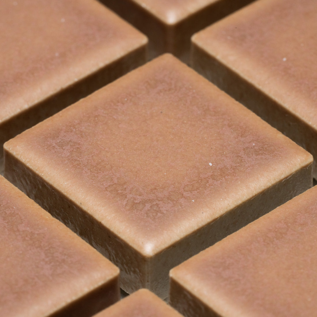 Close-up of Zia Tile's Rhubarb 1x1, featuring square segments with smooth, slightly textured surfaces and sharp edges, arranged in a grid pattern.