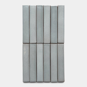 Twelve Roca Mini Bar tiles by Zia Tile in light gray are arranged vertically in a 4x3 grid on a plain white background.