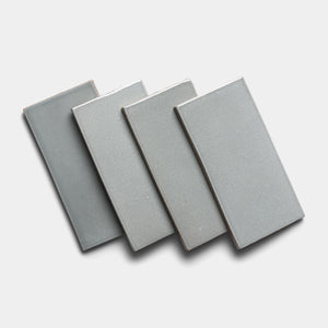 Four Roca 4x8 Rectangle tiles by Zia Tile, featuring a light gray ceramic finish, are arranged in a slightly overlapping diagonal pattern on a plain white background.