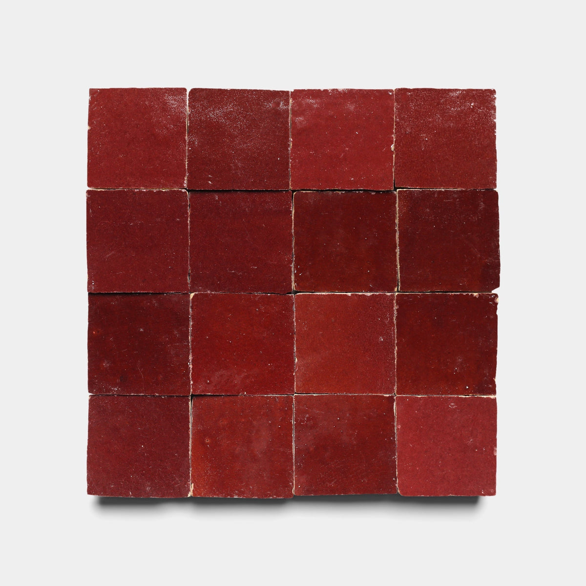 A 4x4 grid of sixteen Zia Tile Rouge 2x2 samples, each showing unique shades and subtle textures, arranged on a plain white background.