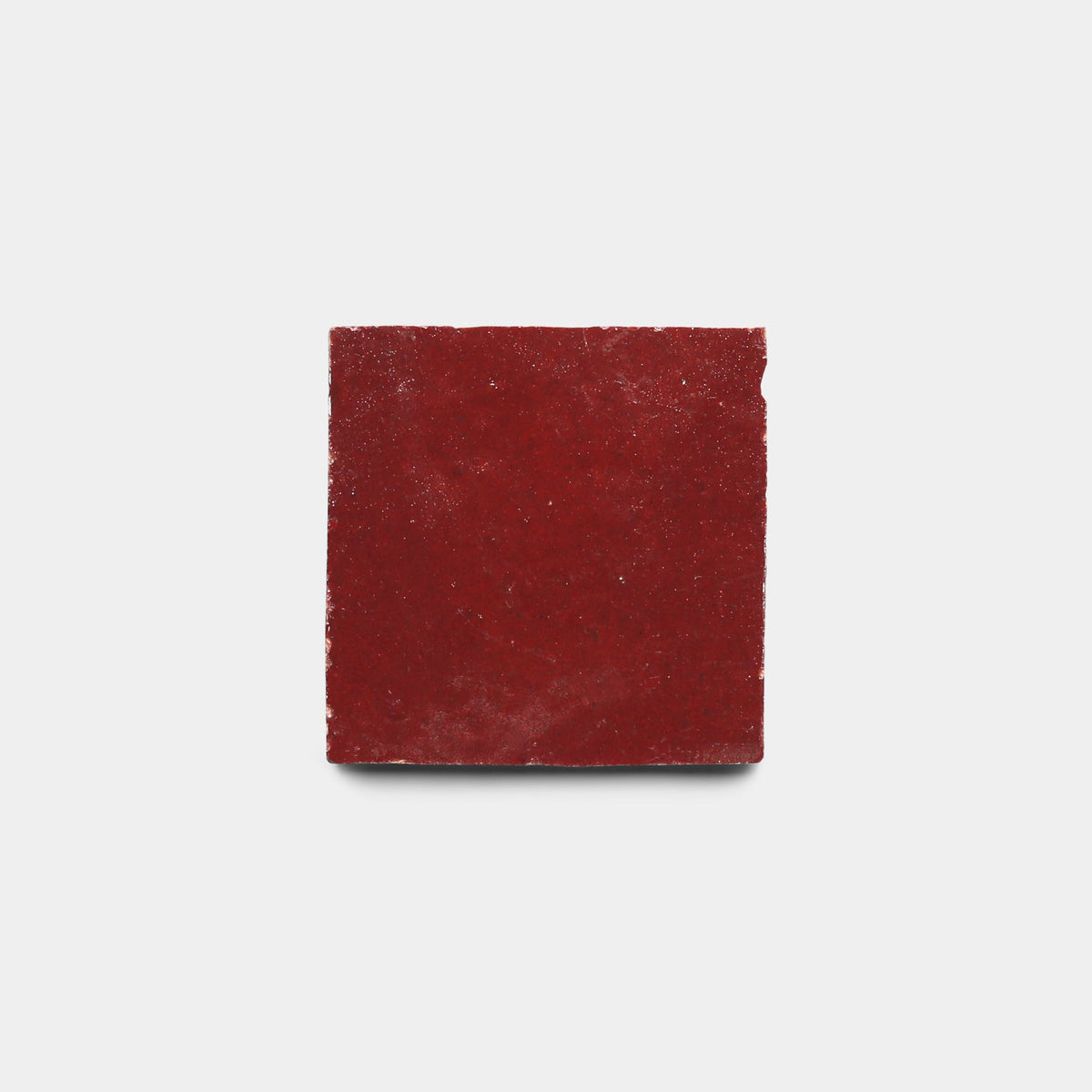A single Rouge 2x2 handmade red tile by Zia Tile, featuring a rough matte finish, is centered on a plain white background.
