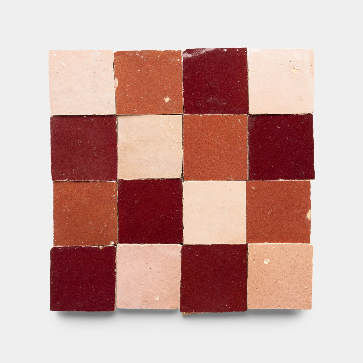 A 16-tile square grid of Zia Tile's Rouge + Terra Rosa + Desert Bloom Checkerboard sample, featuring handmade tiles in red, pink, and terracotta tones arranged on a plain light background.