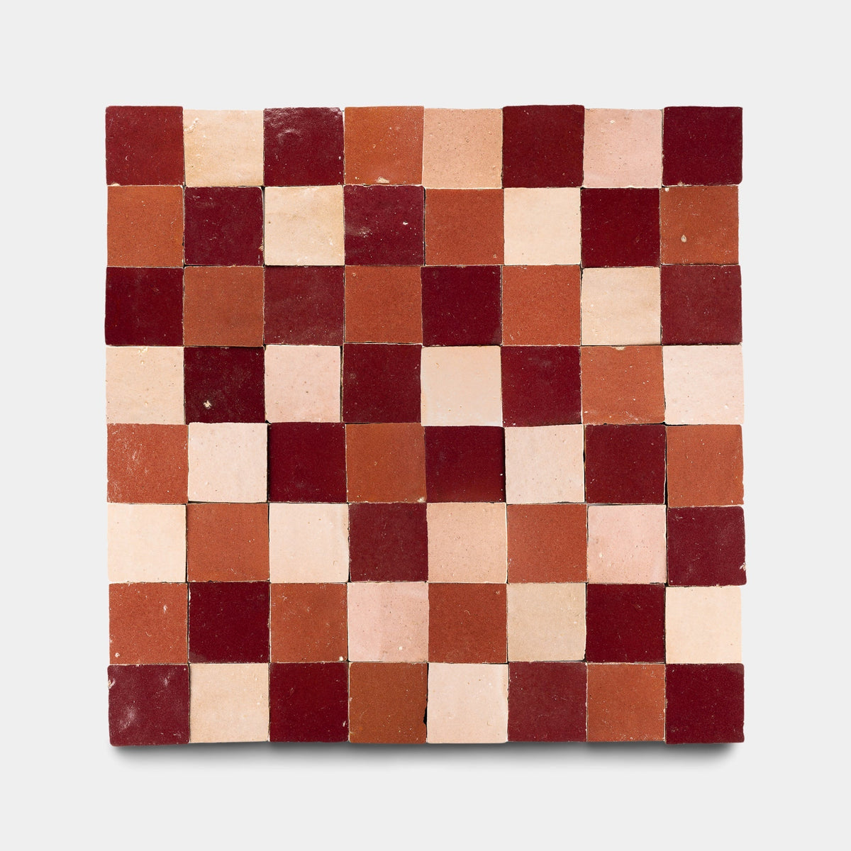 A sample of Zia Tile's Rouge + Terra Rosa + Desert Bloom Checkerboard features small, handmade ceramic tiles in alternating shades on a plain white background.